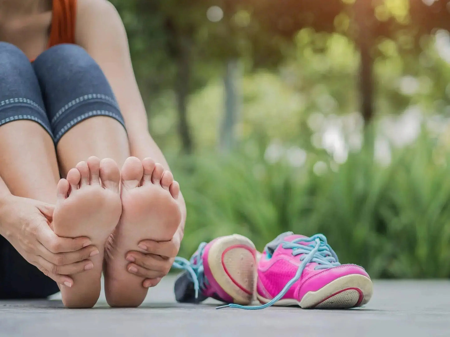 Woman holding sore foot, representing foot pain conditions like neuropathy, plantar fasciitis, and hammertoe that NeuroSox therapeutic socks help support