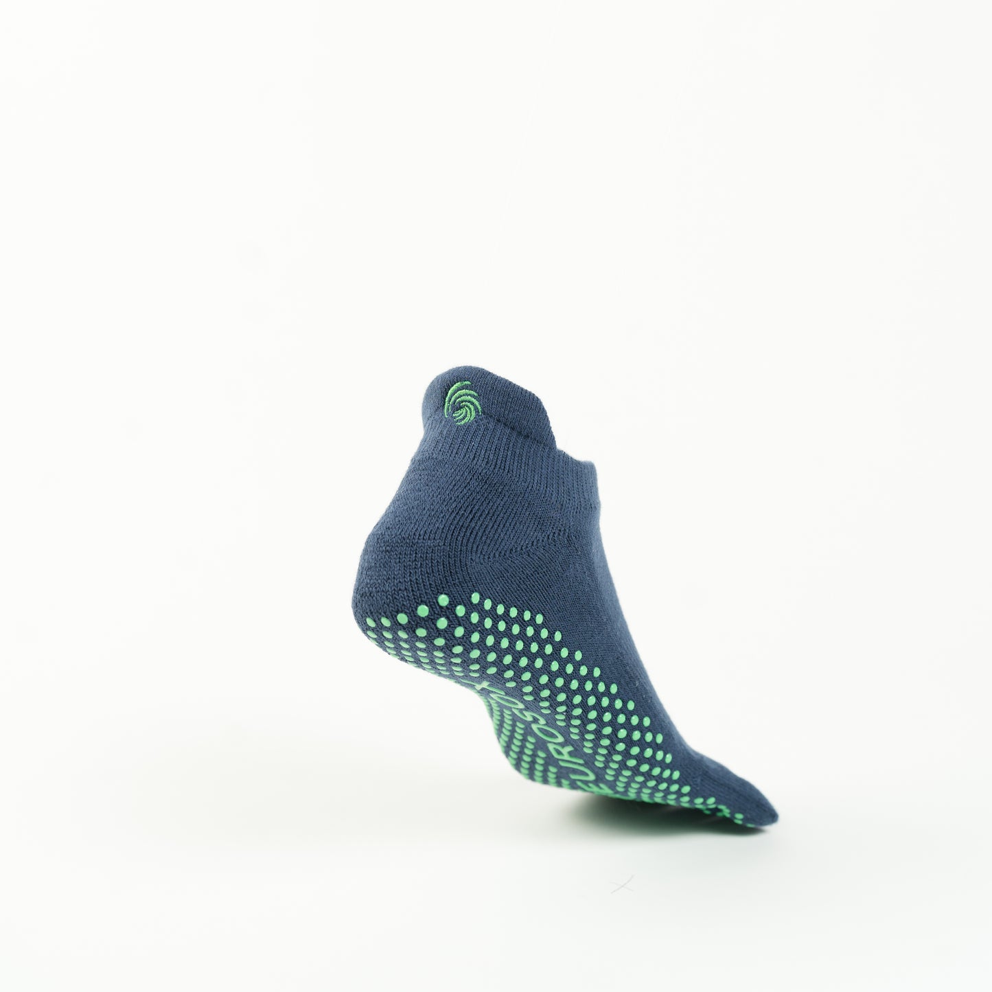 The image shows a single navy colored sock with green grip dots on the sole, positioned as if suspended in mid-air against a plain white background. The sock has a small green swirl logo near the ankle area.