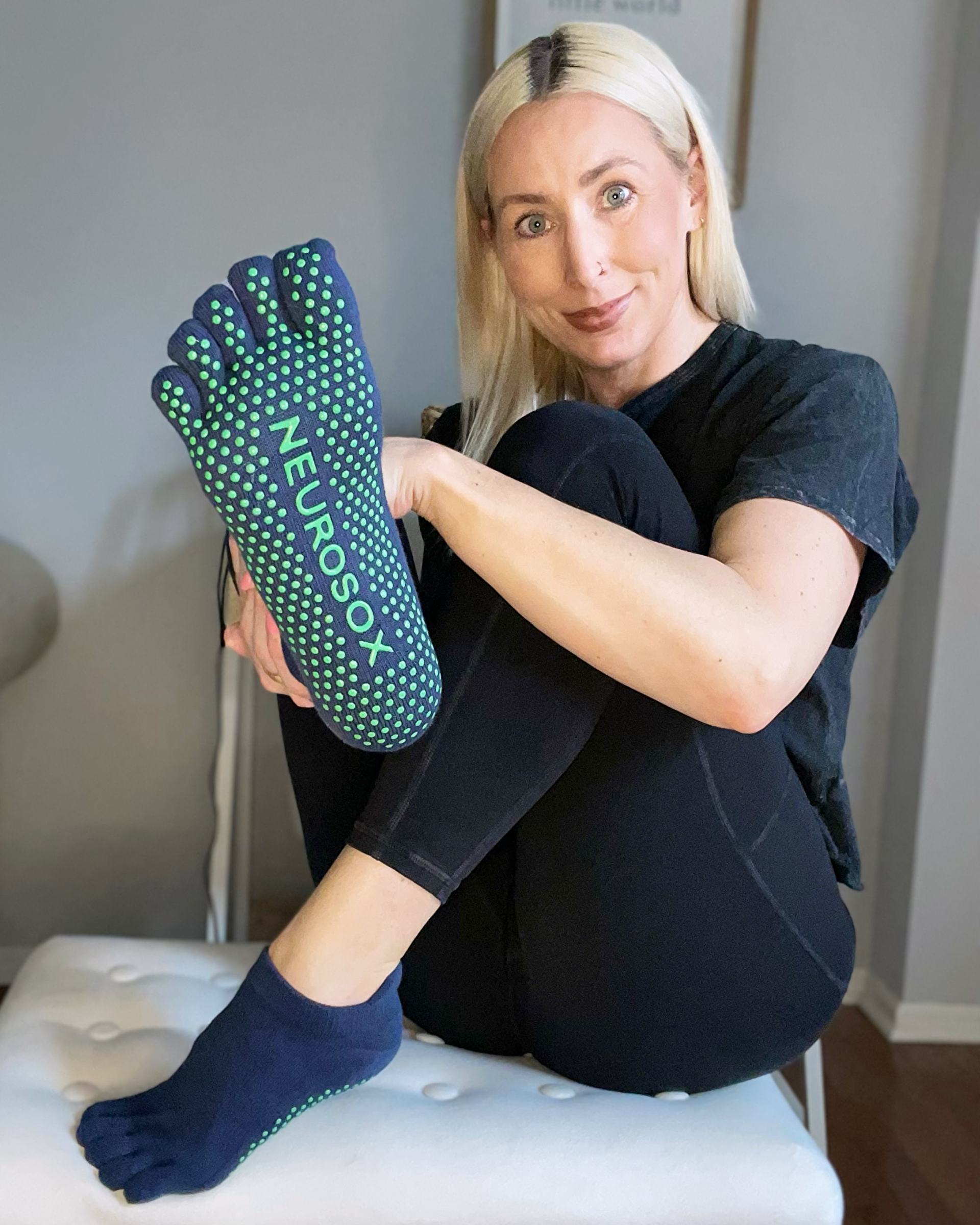 Woman wearing black NeuroSox five toe socks while stretching on a yoga mat indoors