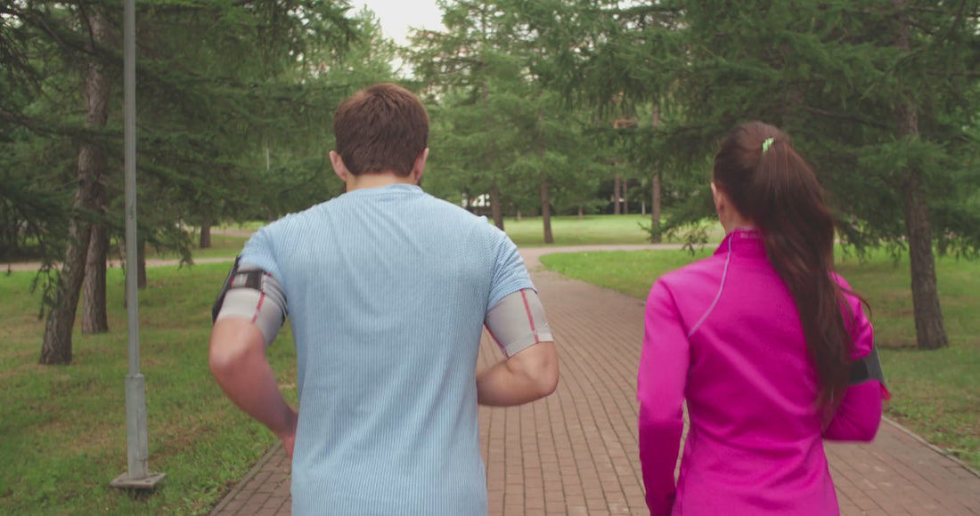 Video of a man and woman running outside on a paved path in a park