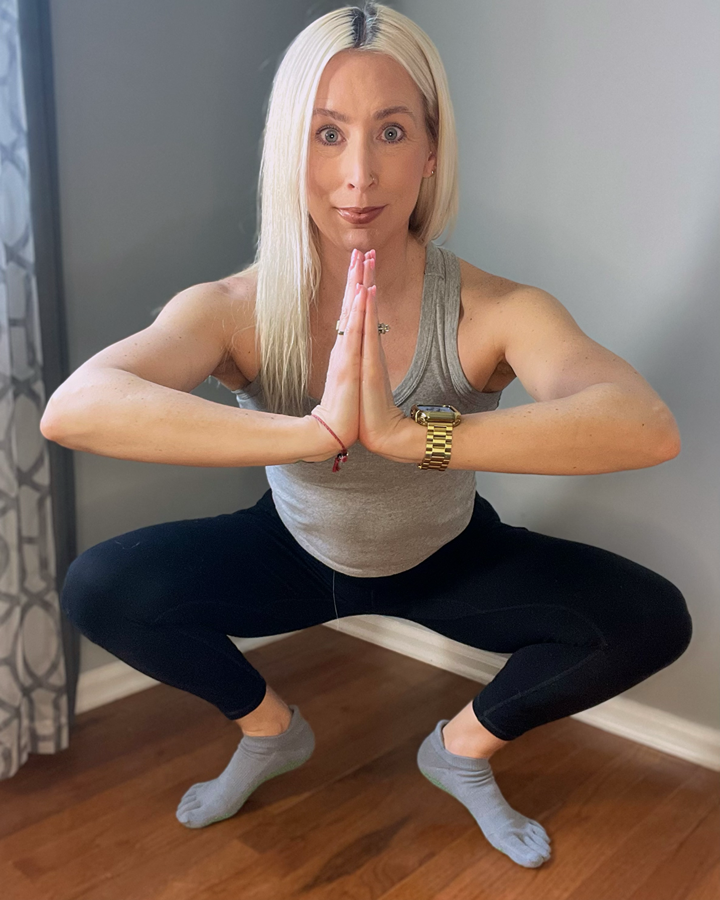 
                  
                    Woman in a yoga squat pose indoors, wearing gray five toe NeuroSox that separate toes and grip the floor.
                  
                
